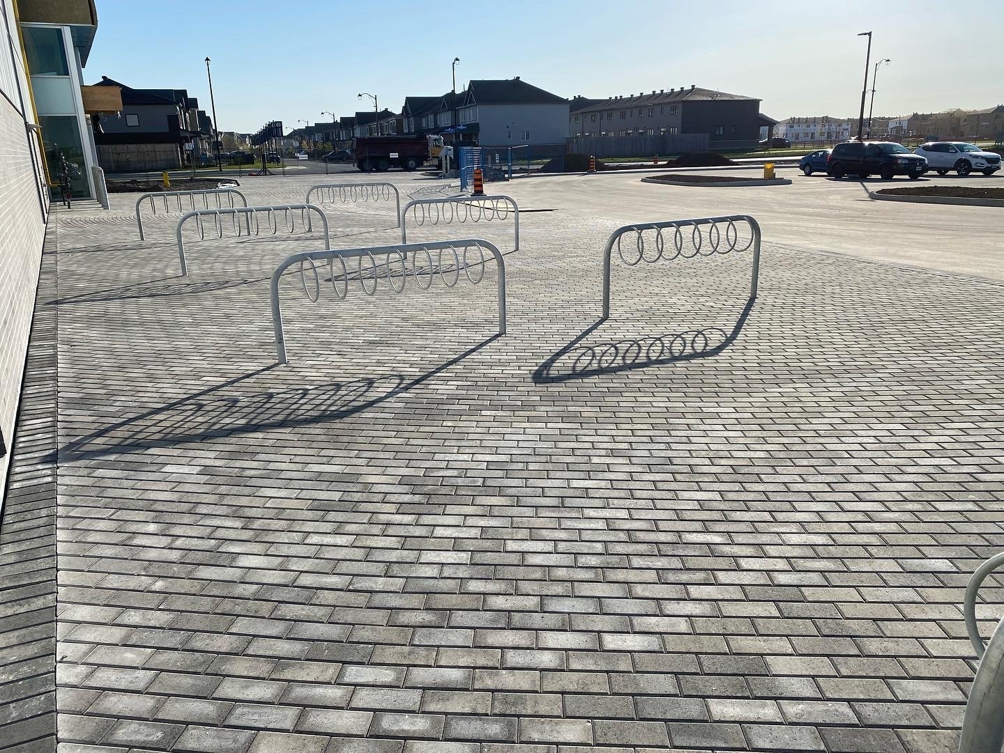 Empty curved bike racks on paved sidewalk.