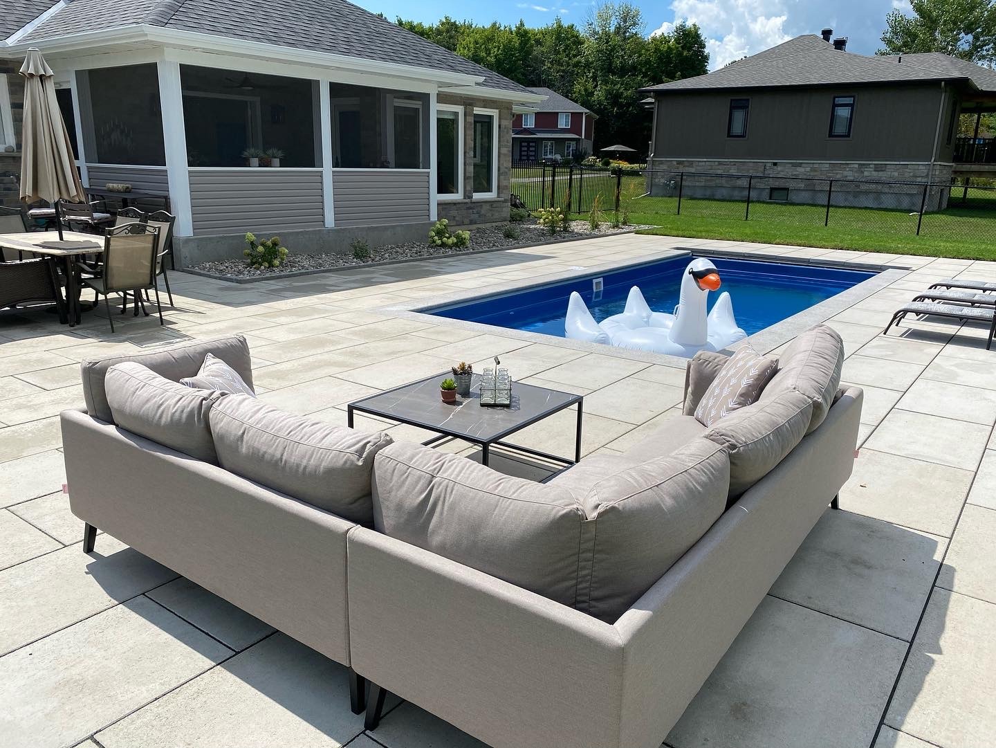 Poolside patio with swan floater and seating.