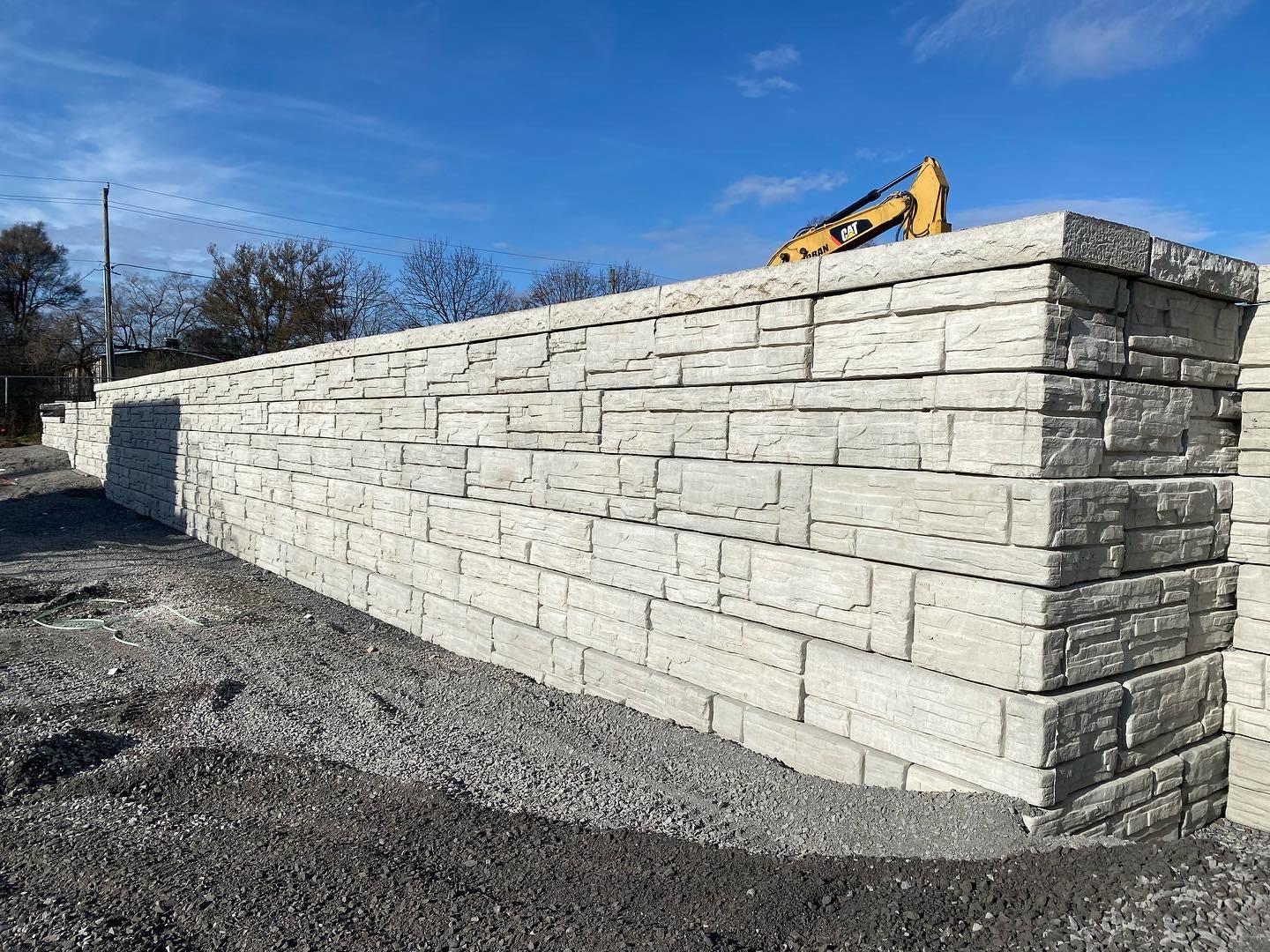 Construction site with stone retaining wall and machinery.