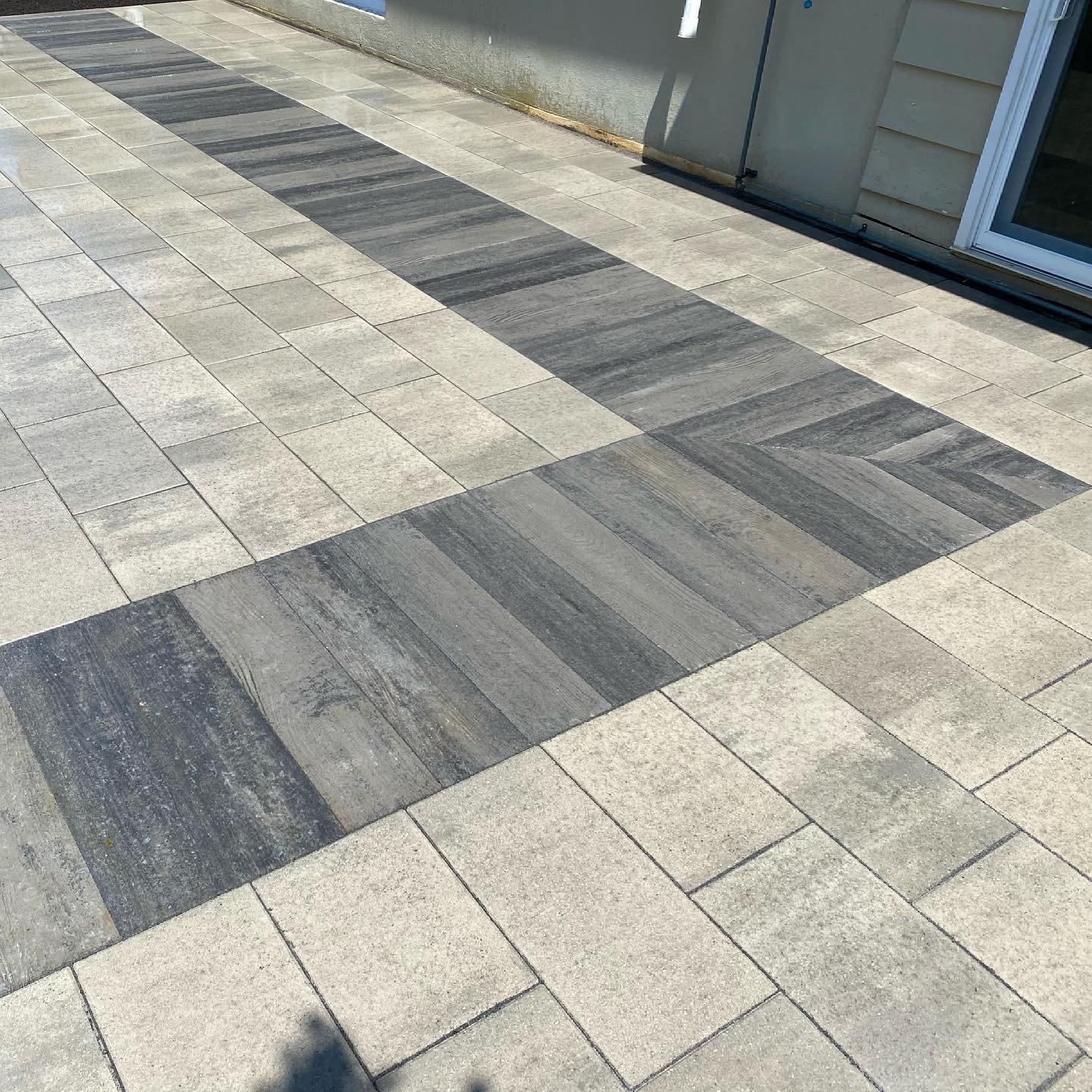 Patterned stone patio with light and dark tiles.