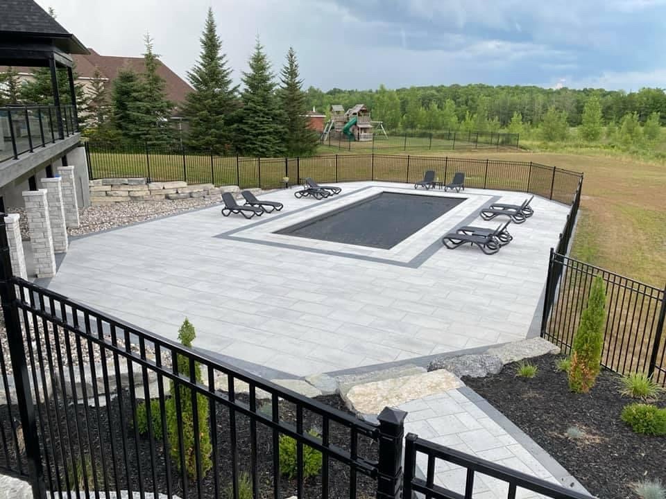 Outdoor pool with lounge chairs and forest view.