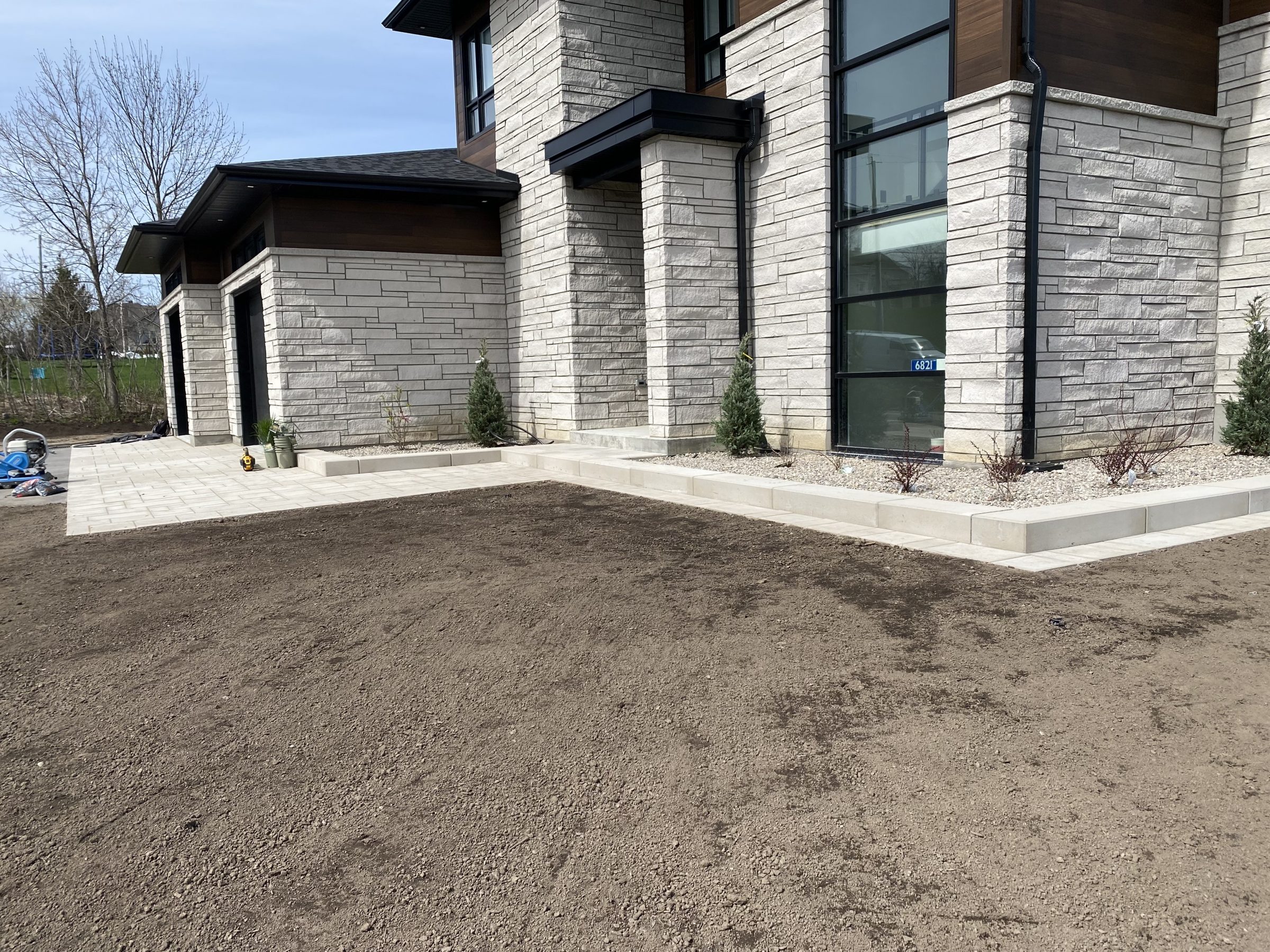 Modern stone house with landscaped front yard.