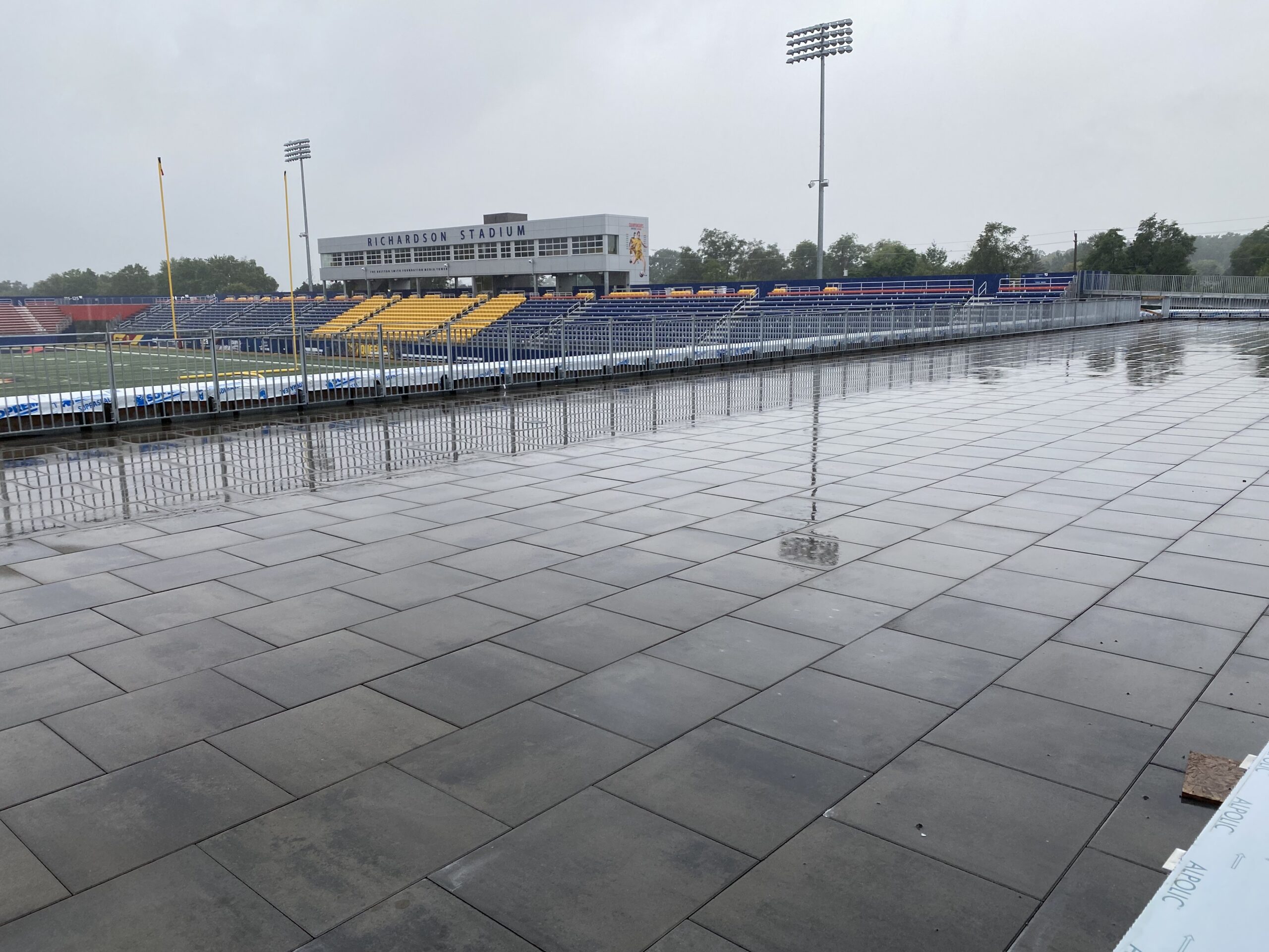 Empty stadium with wet pavement on rainy day.