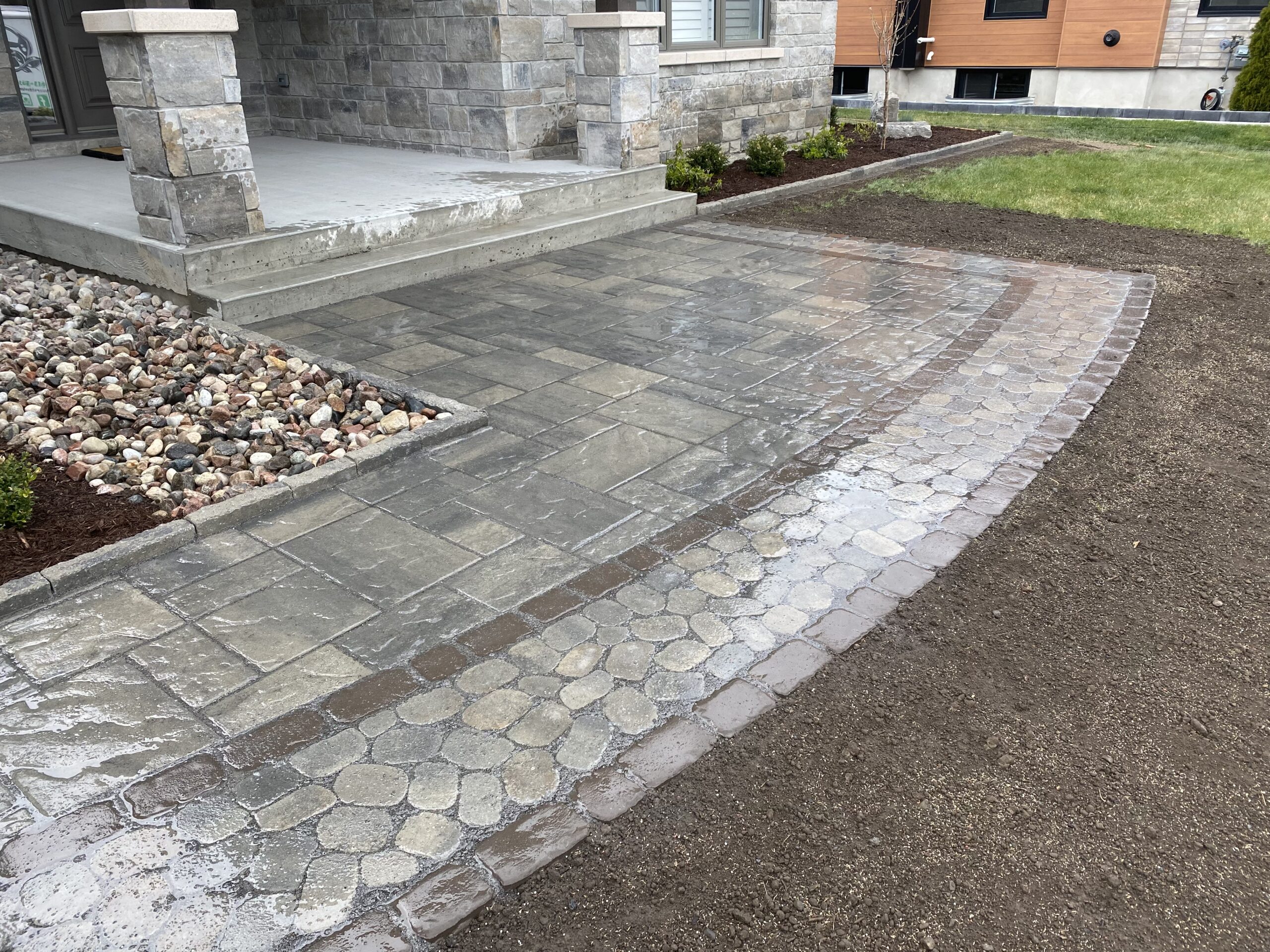 Wet stone patio and walkway near house entrance.