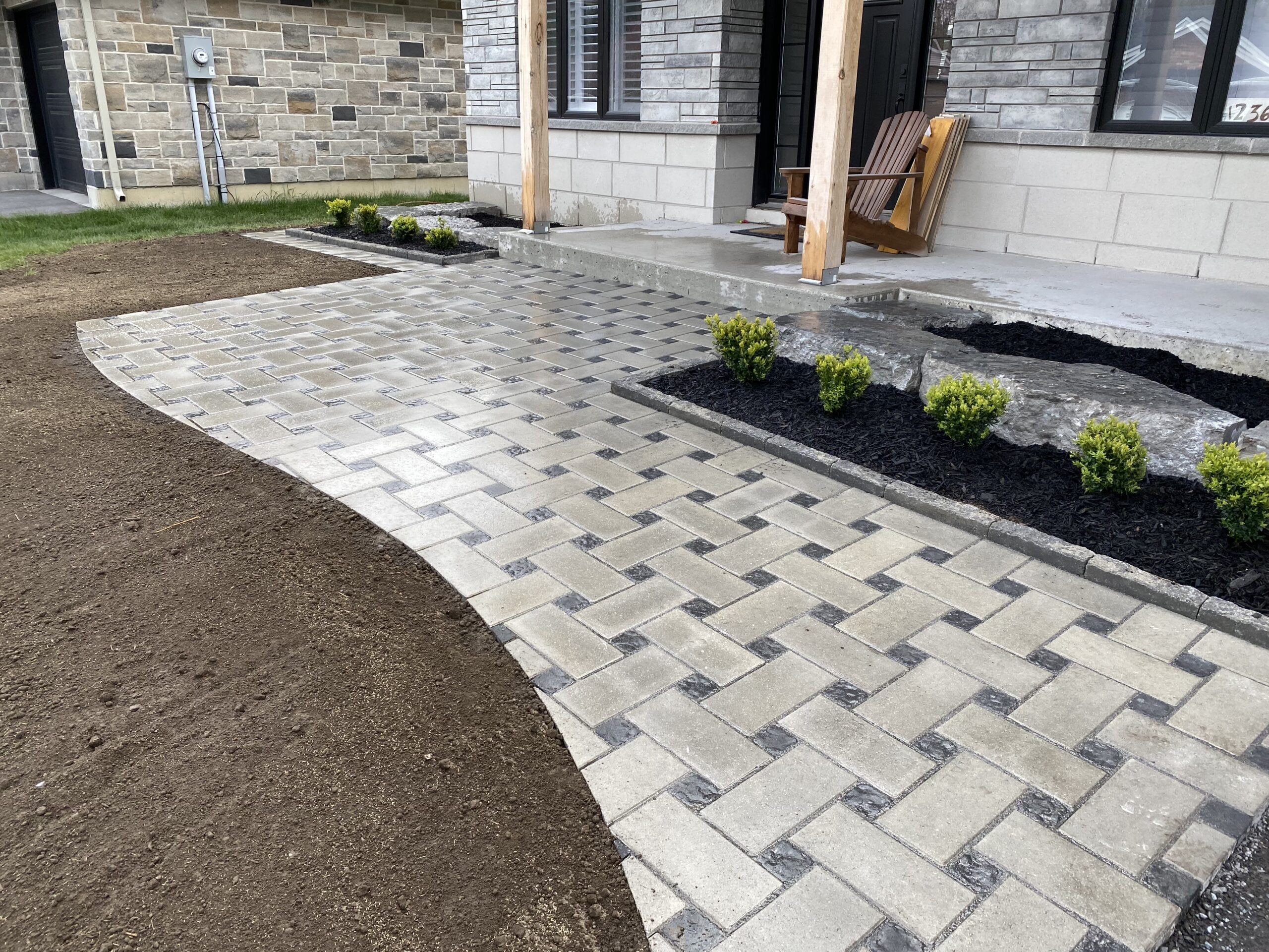 Brick pathway with garden landscaping in front of house.