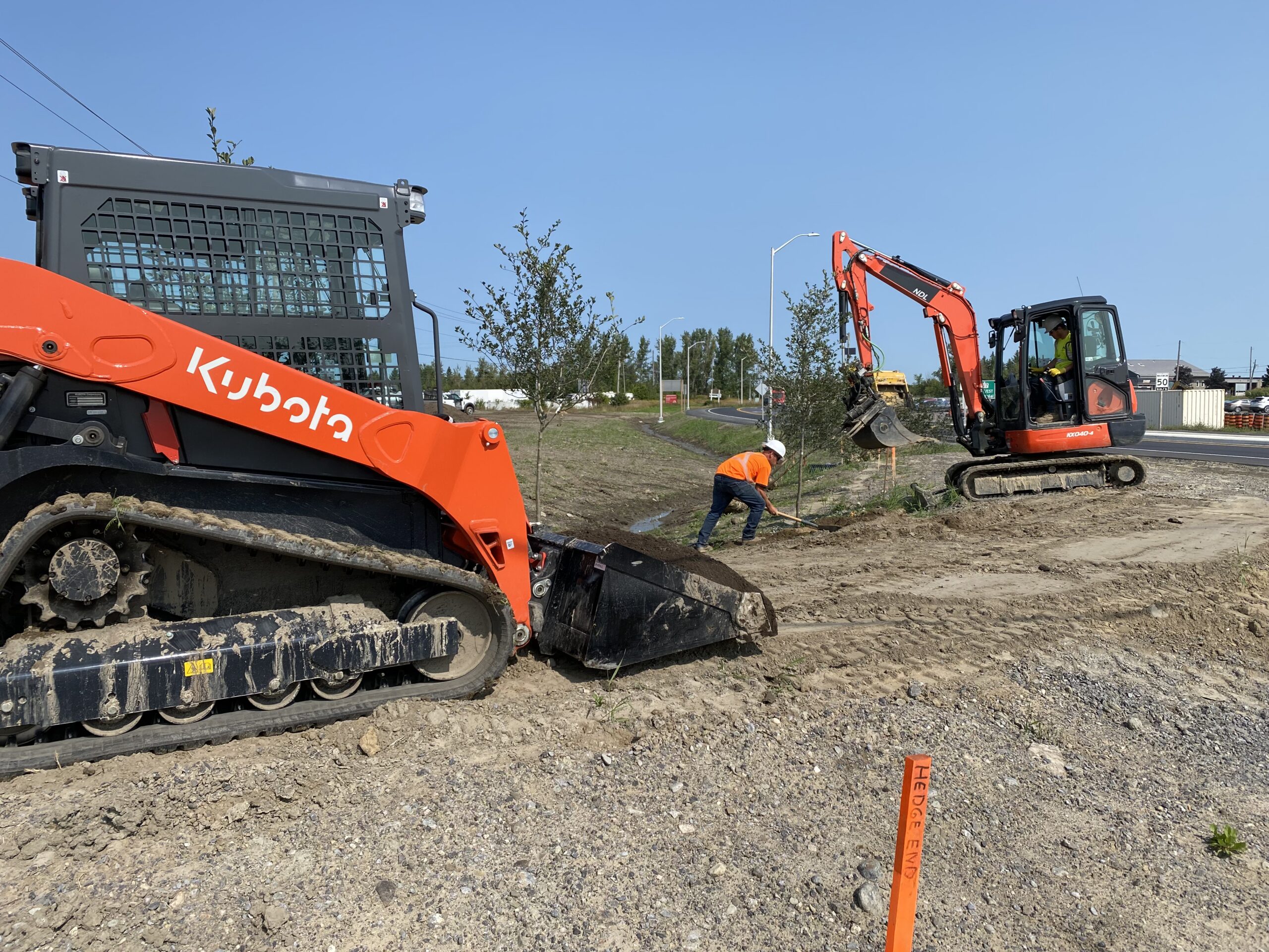 Workers using excavators for roadside construction