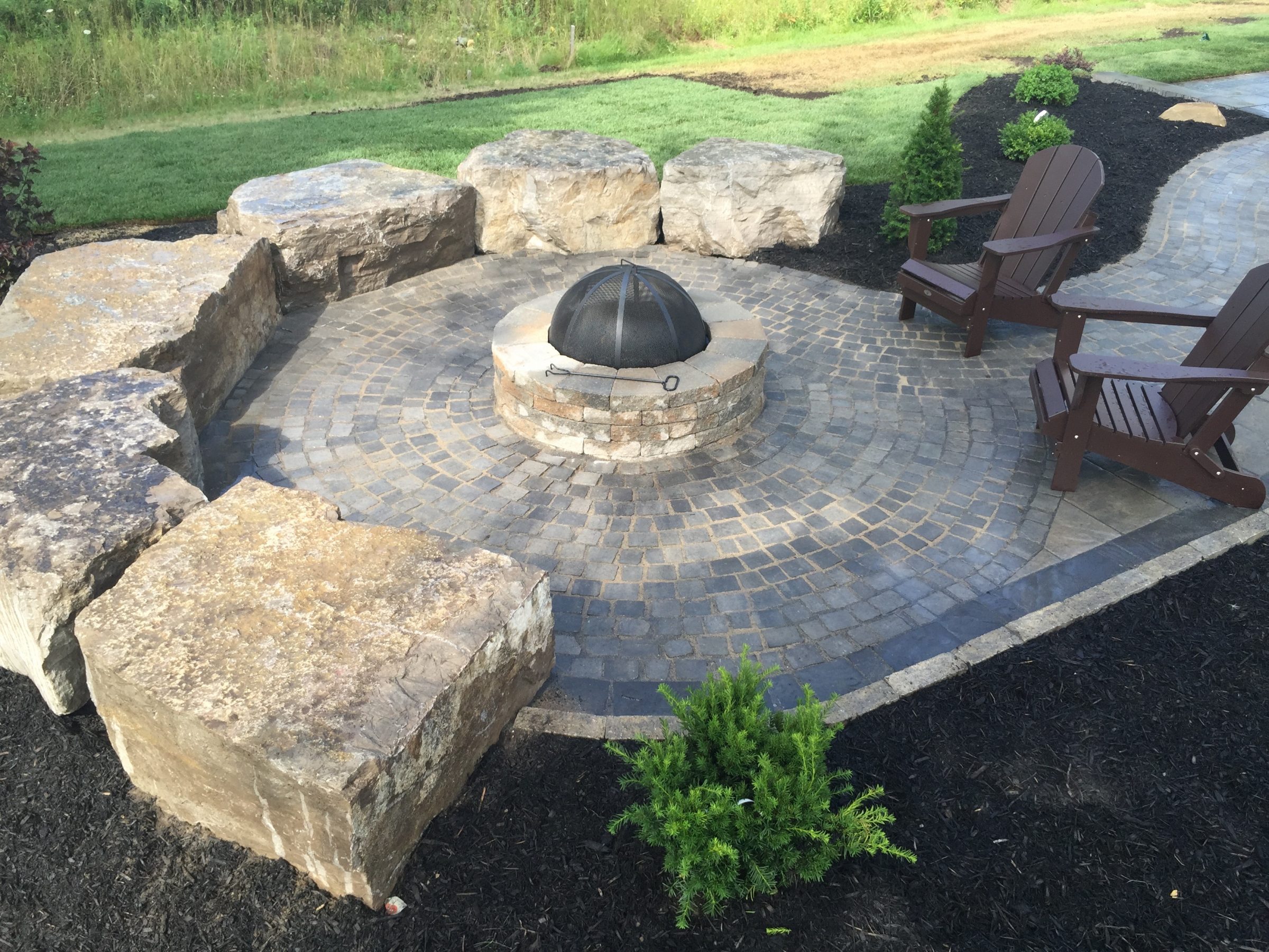 Stone patio with fire pit and chairs.