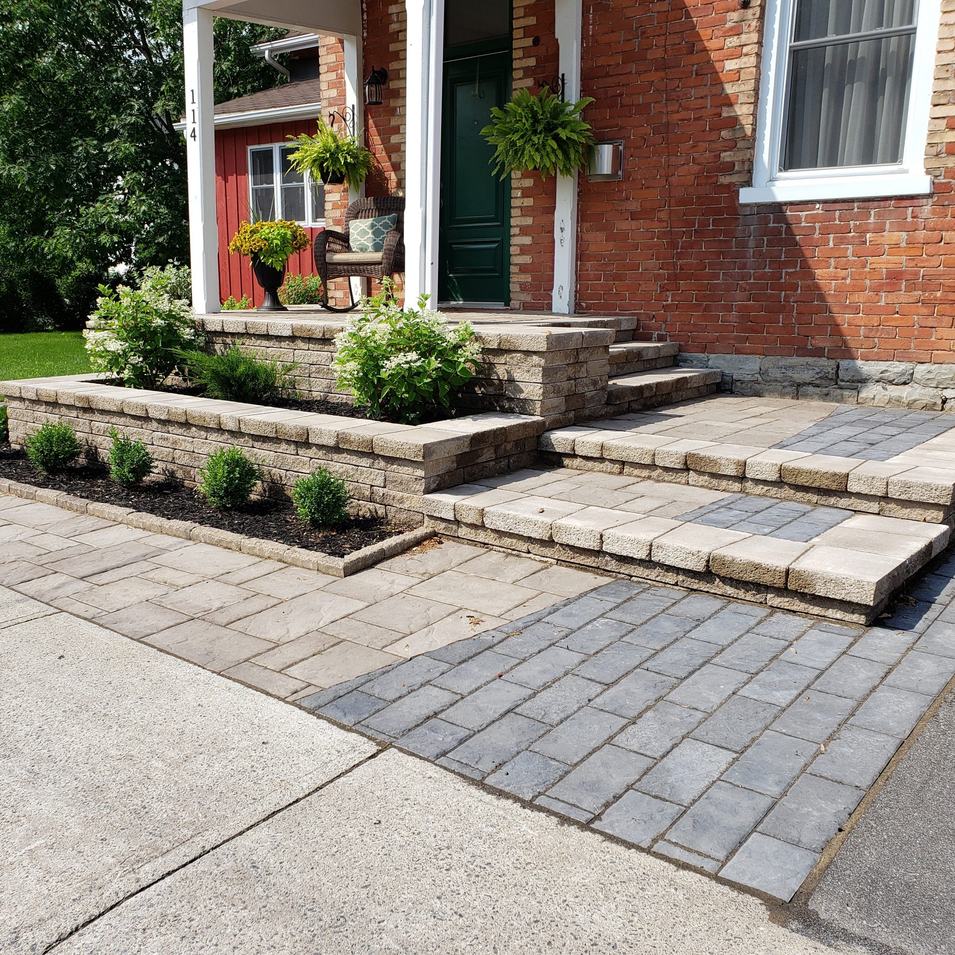 Brick house entrance with porch and plants.