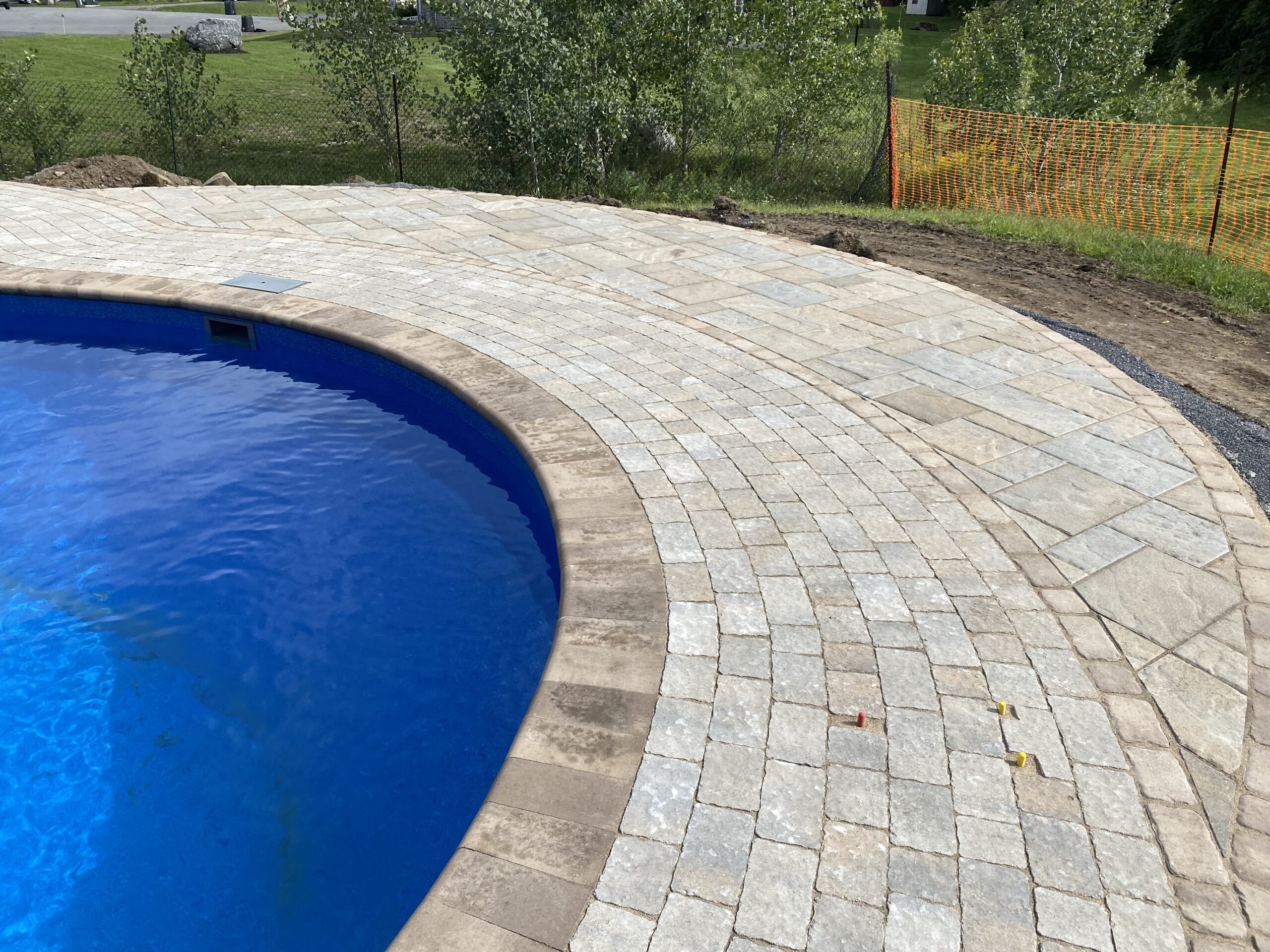 Stone patio surrounding blue swimming pool.
