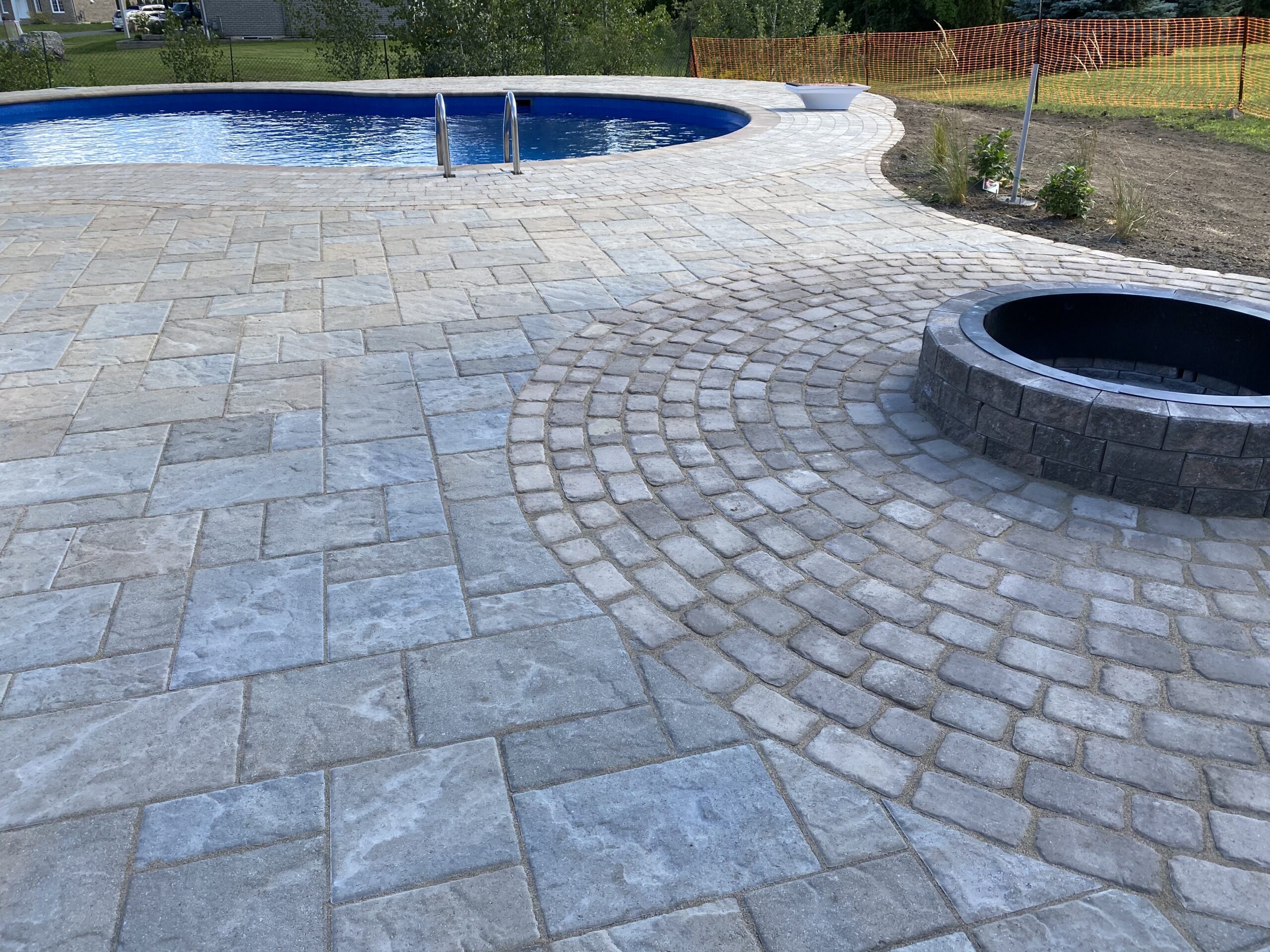 Outdoor stone patio with pool and firepit.
