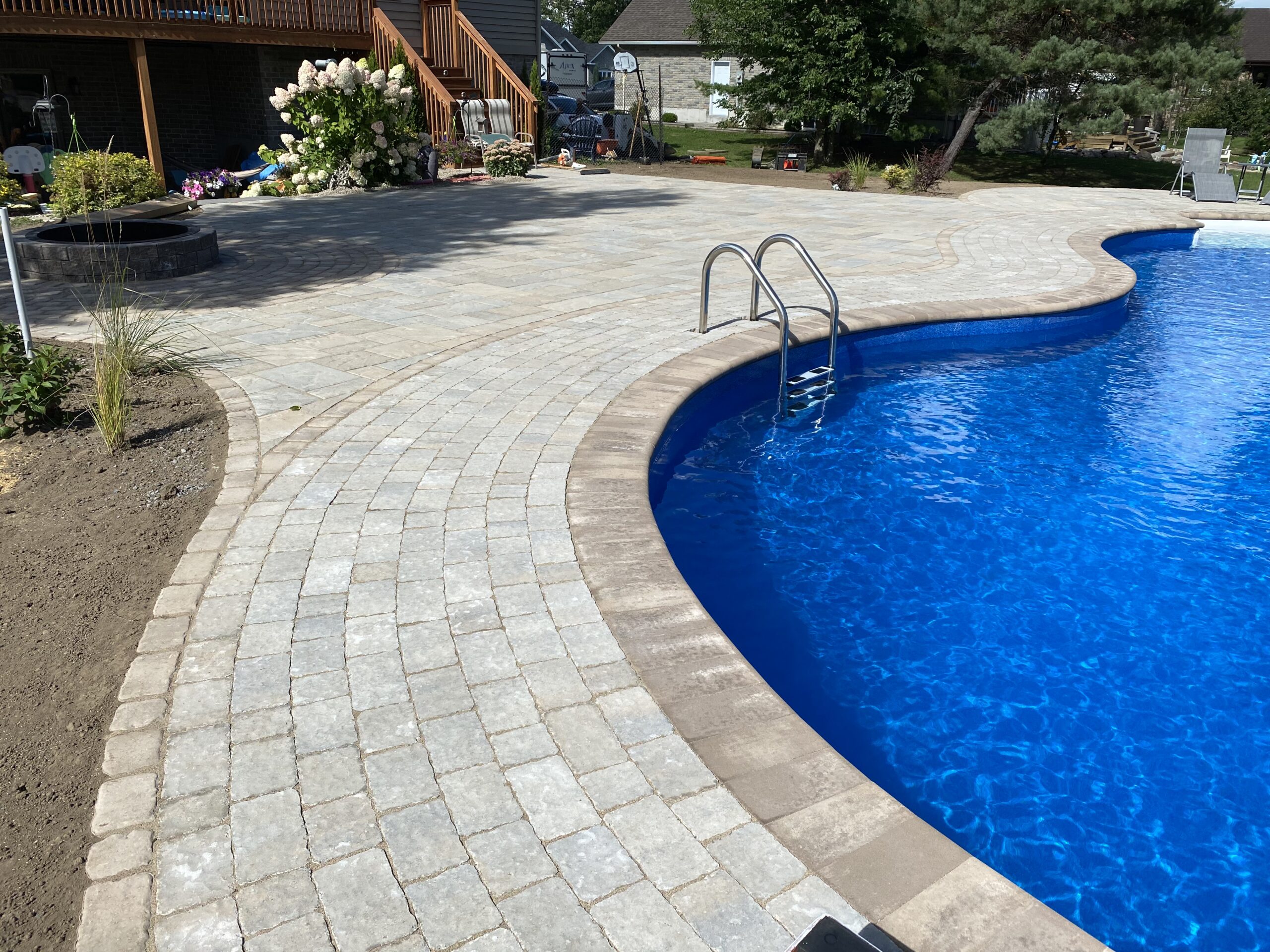 Backyard pool with stone patio and garden.