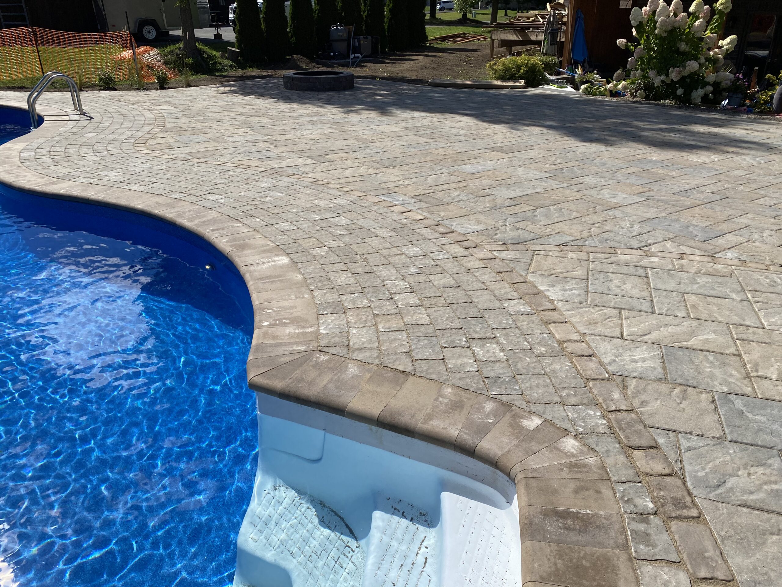 Stone pool deck with blue water and steps.