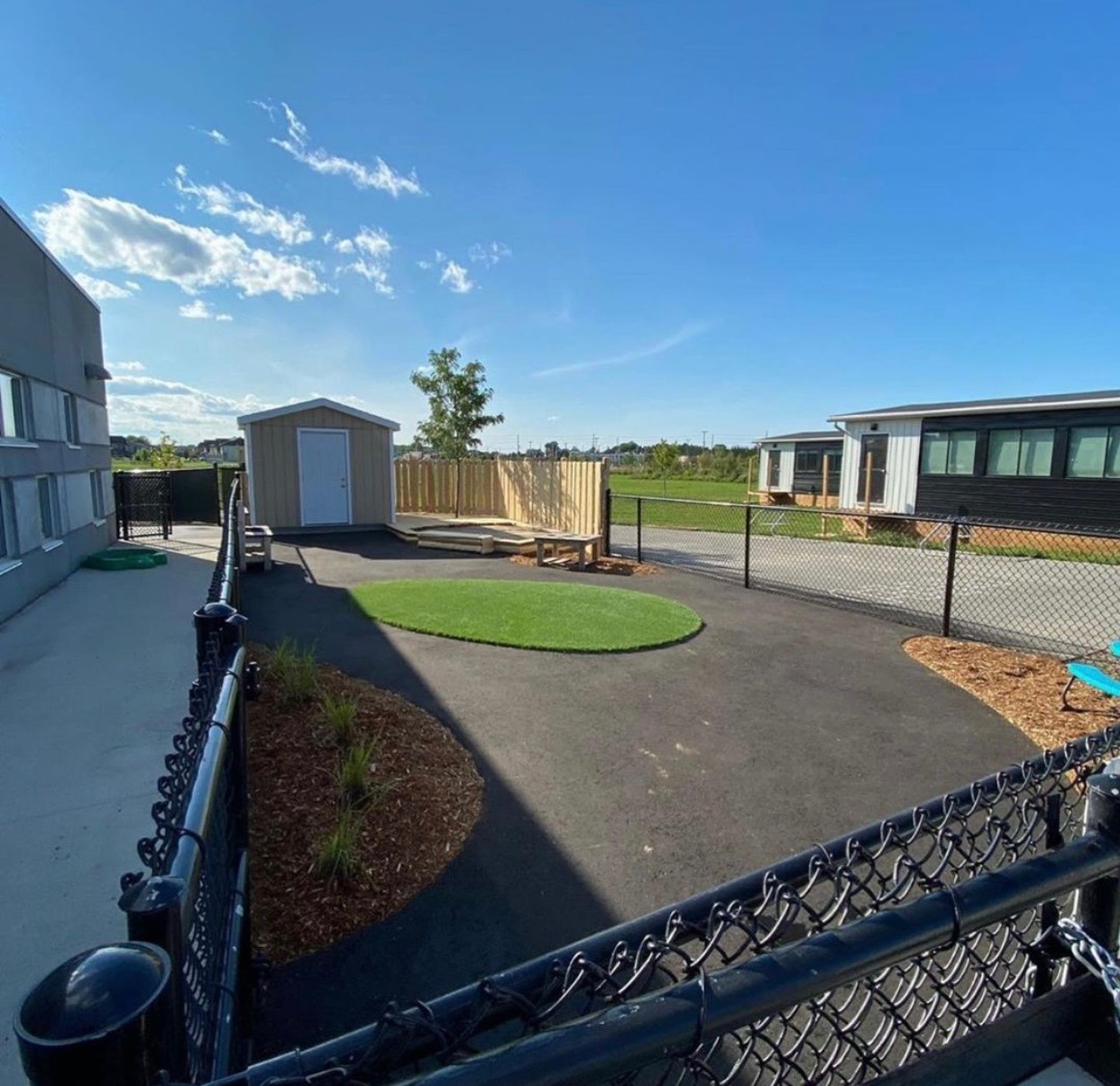 Modern schoolyard with fenced playground and sunny sky.