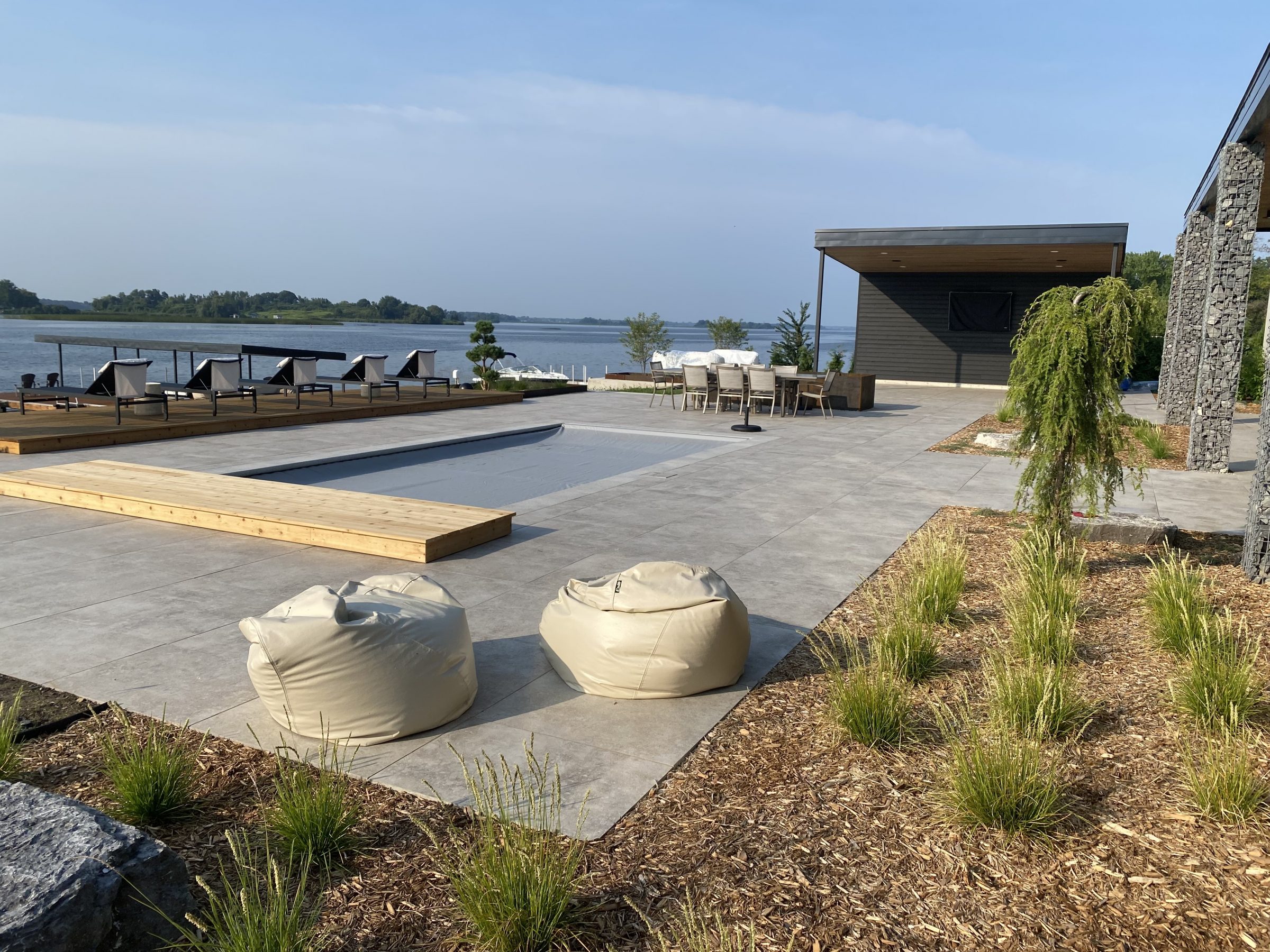 Modern lakeside patio with pool and seating area.