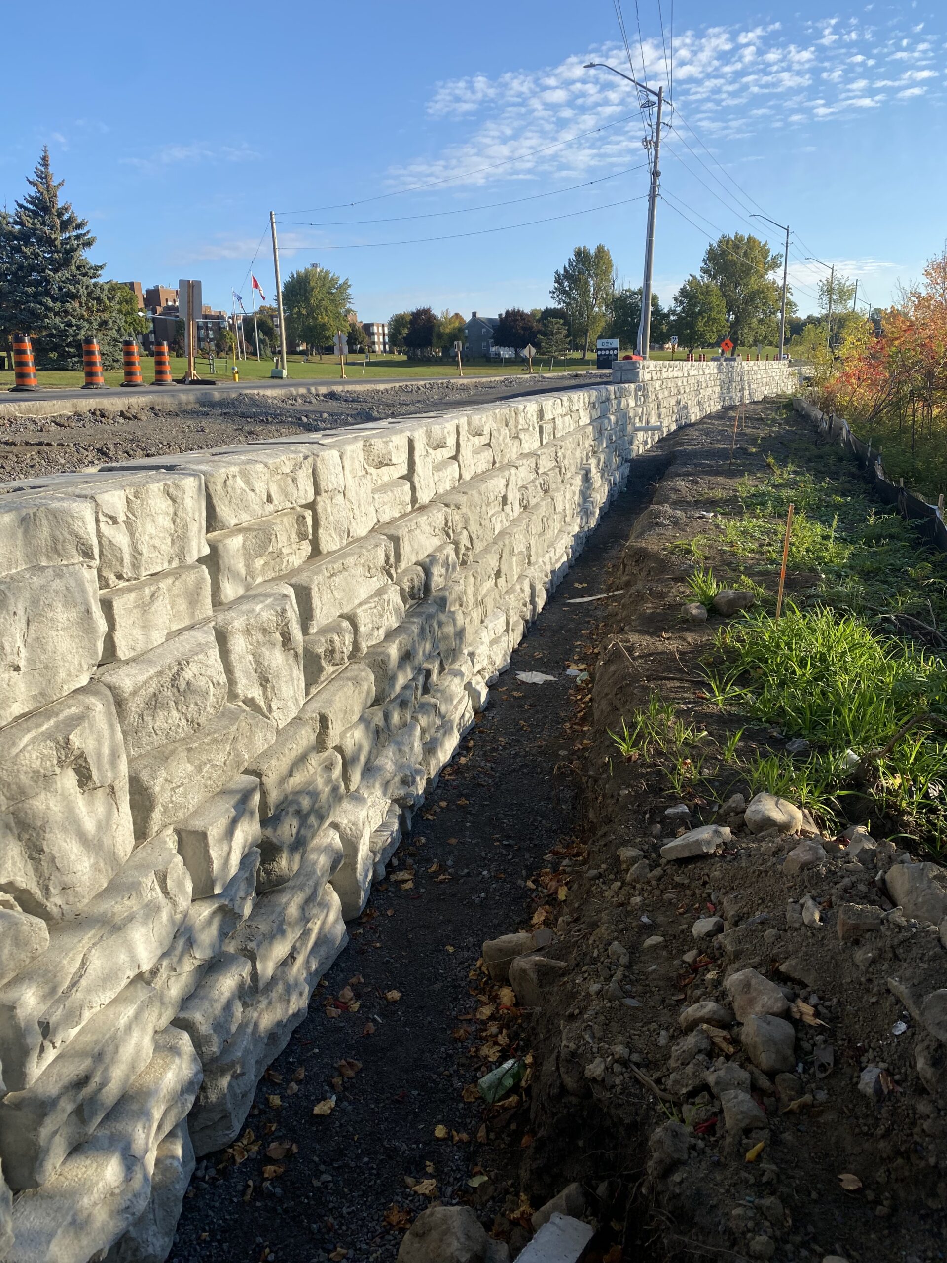 Stone retaining wall by roadside under clear sky