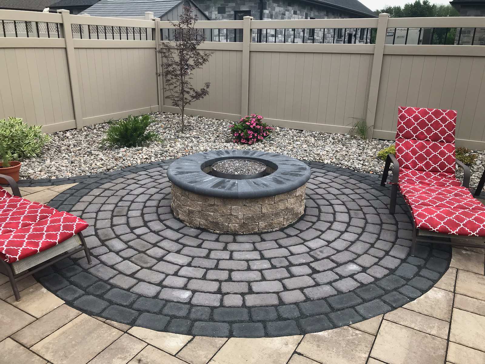 Patio with circular stone fire pit and chairs.