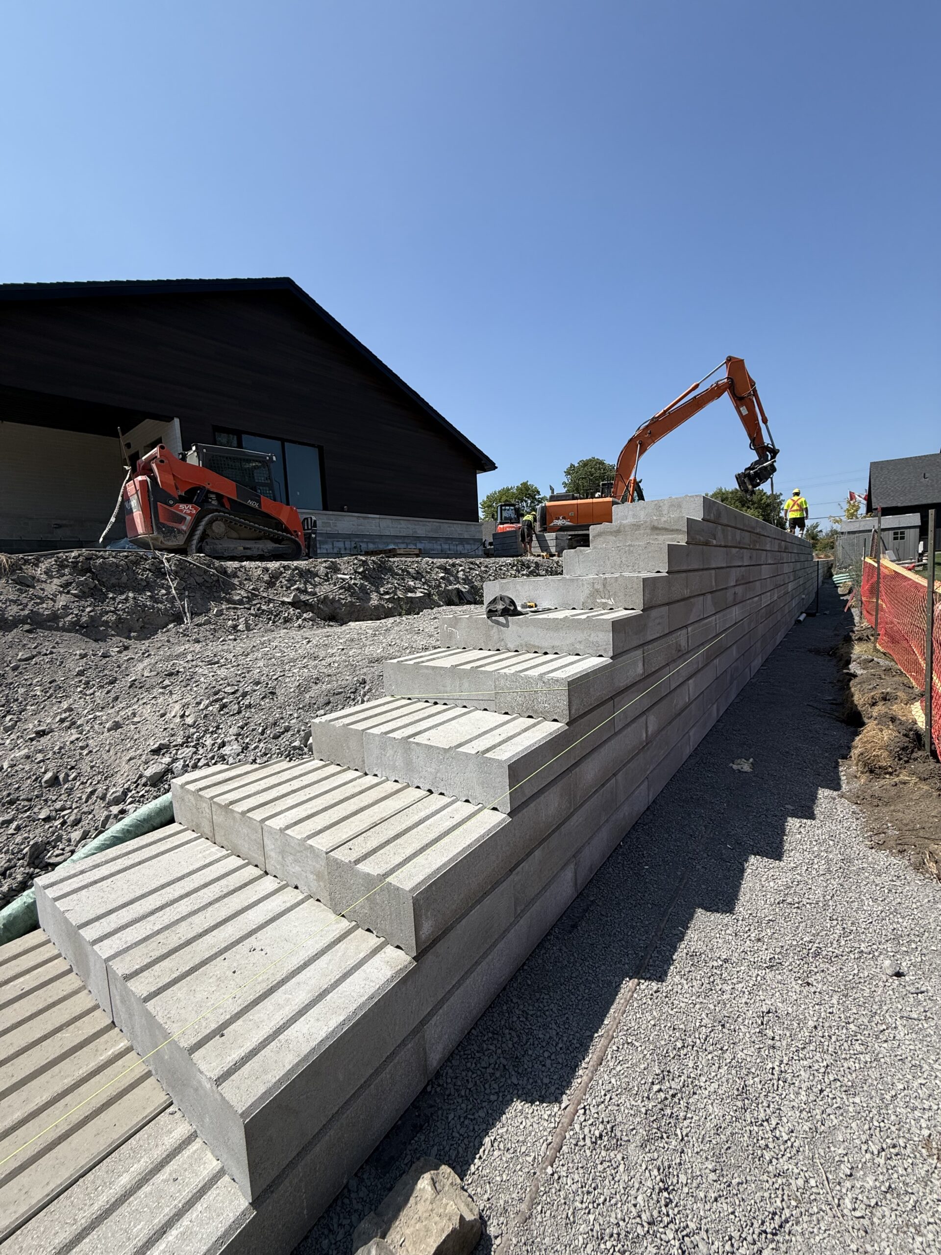 Construction site with excavator and large concrete blocks.