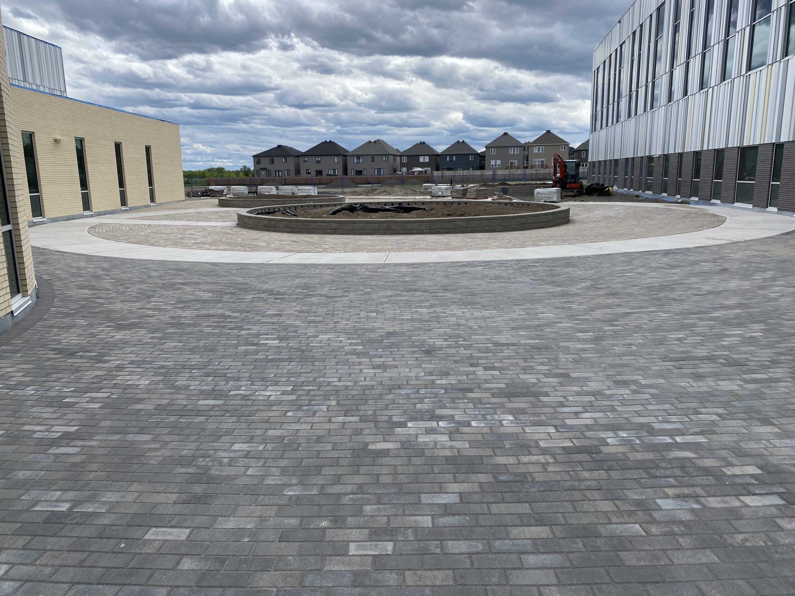Paved courtyard with modern building and cloudy sky.