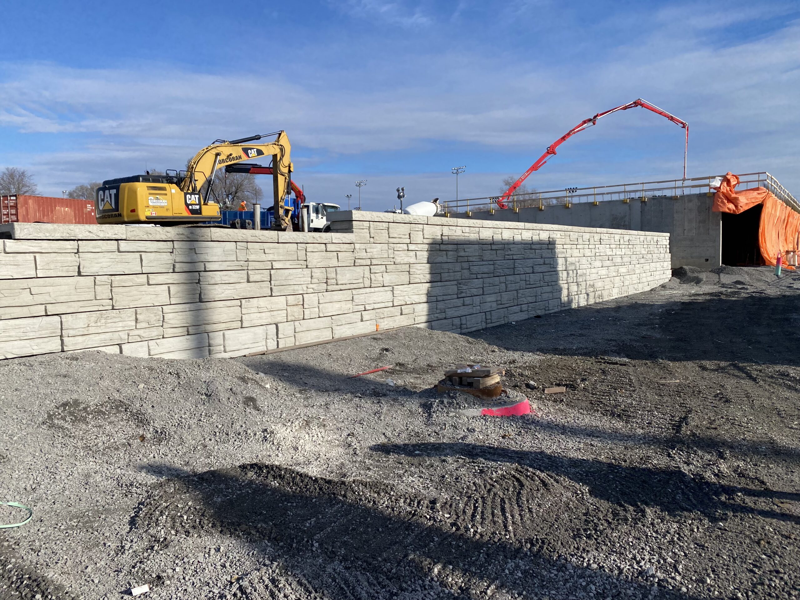 Construction site with excavator and stone wall.