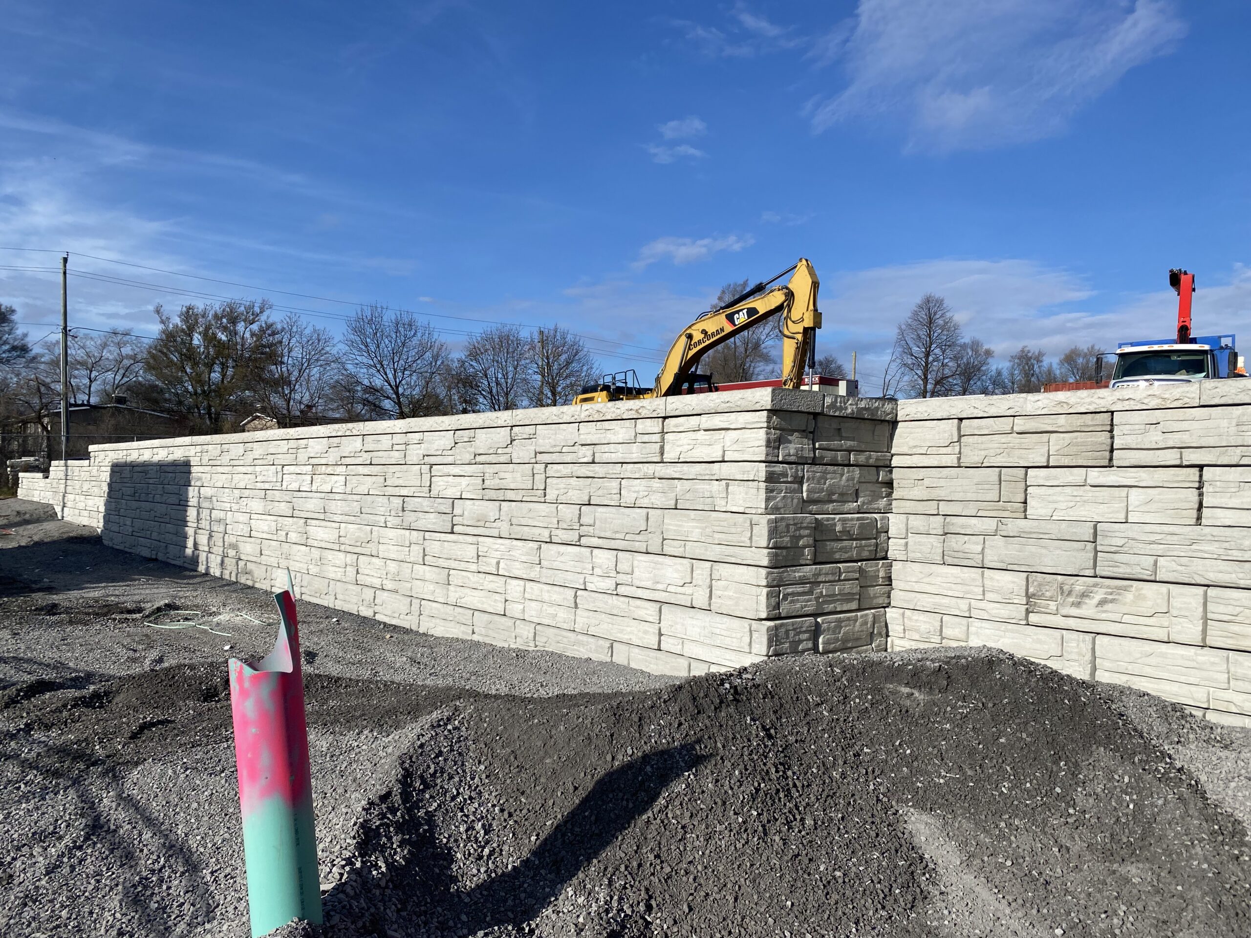 Stone retaining wall with construction equipment nearby.