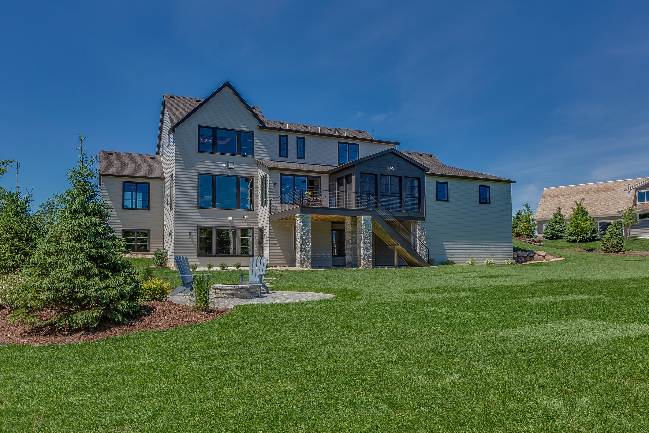 Modern house with large backyard and blue sky.