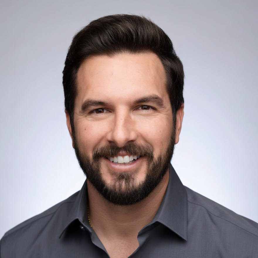 Smiling man with beard in gray shirt.